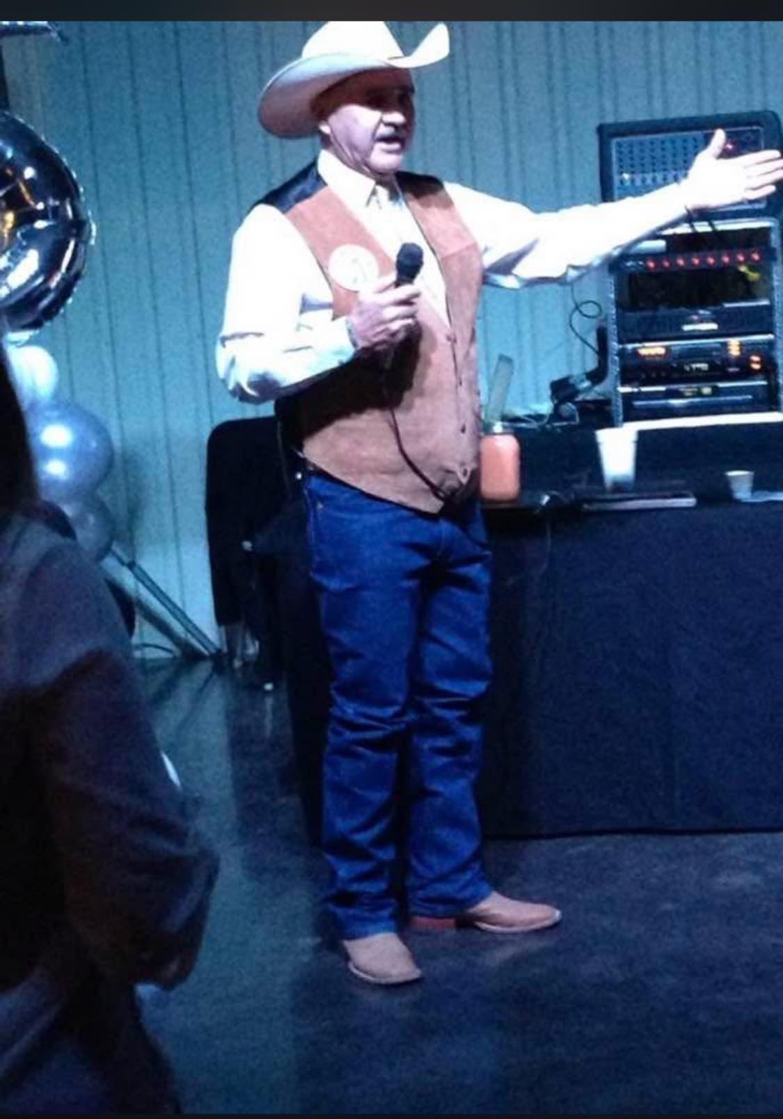 Man gesturing near sound equipment at gathering