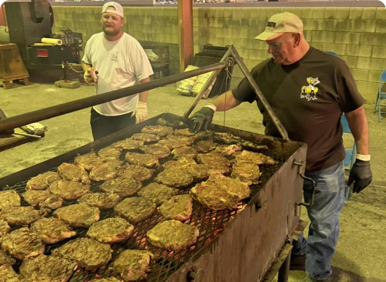 Two men cooking steaks on barbecue grill