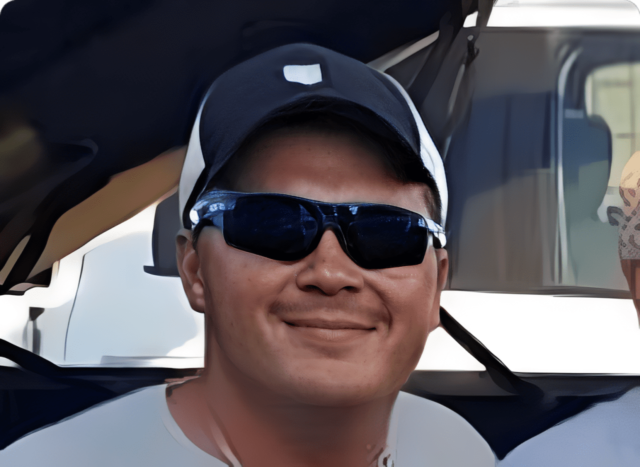 Man wearing sunglasses and a cap smiling