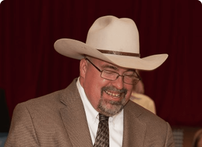 Man wearing cowboy hat and glasses smiling